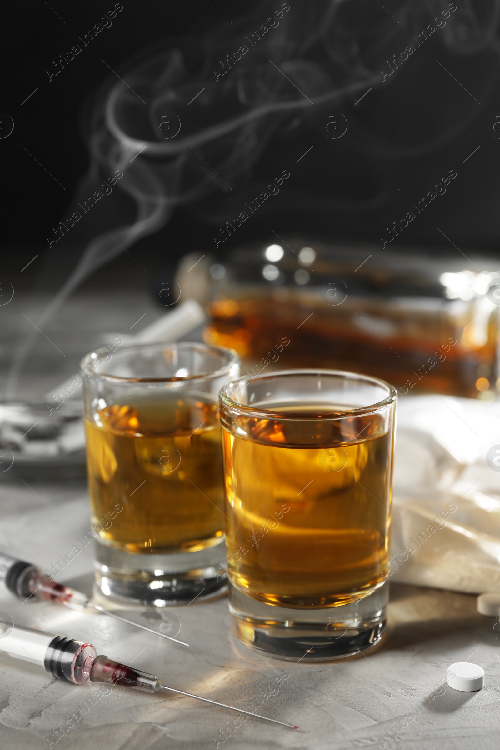 Photo of Alcohol and drug addiction. Whiskey in glasses, syringes and pills on grey background