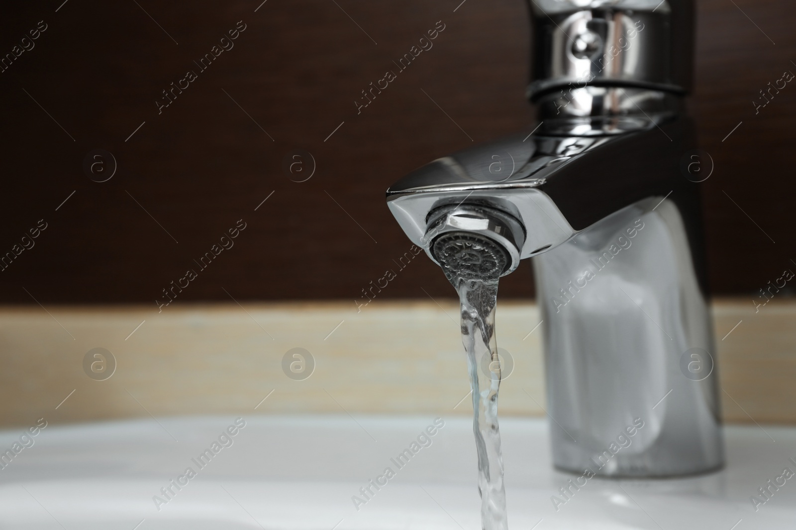 Photo of Closeup view of water flowing from faucet indoors. Space for text