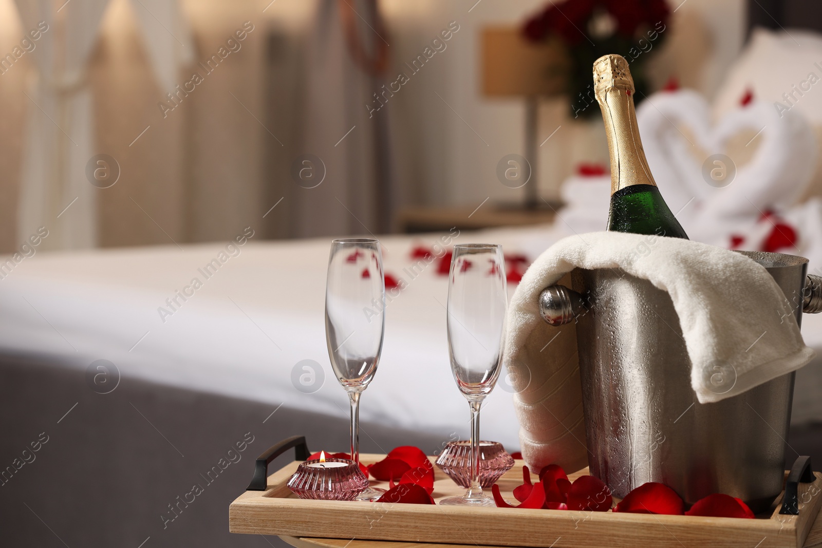 Photo of Honeymoon. Sparkling wine and glasses on wooden table in room. Space for text