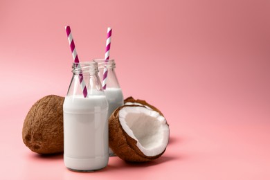 Photo of Delicious vegan milk and coconuts on pink background, space for text