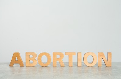 Photo of Word Abortion made of wooden letters on grey table