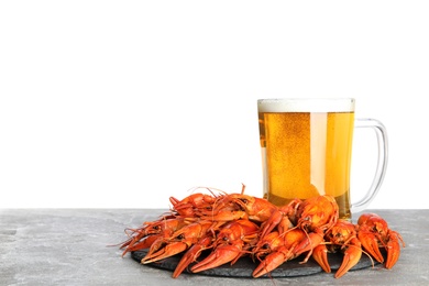 Photo of Delicious red boiled crayfishes and mug of beer on grey table against white background