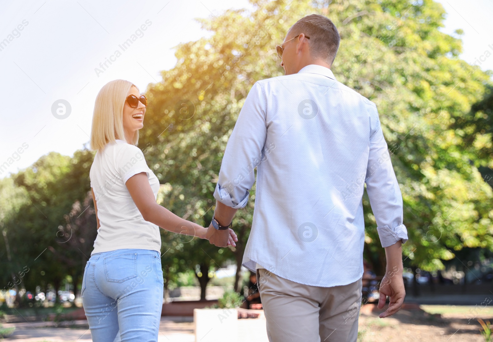 Photo of Happy couple walking along park on summer day