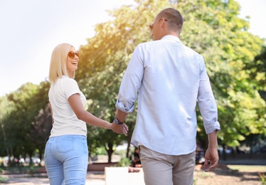 Happy couple walking along park on summer day