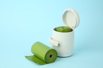 Photo of Dog waste bags and dispenser on light blue background