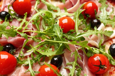 Tasty pizza with meat and arugula as background, closeup view