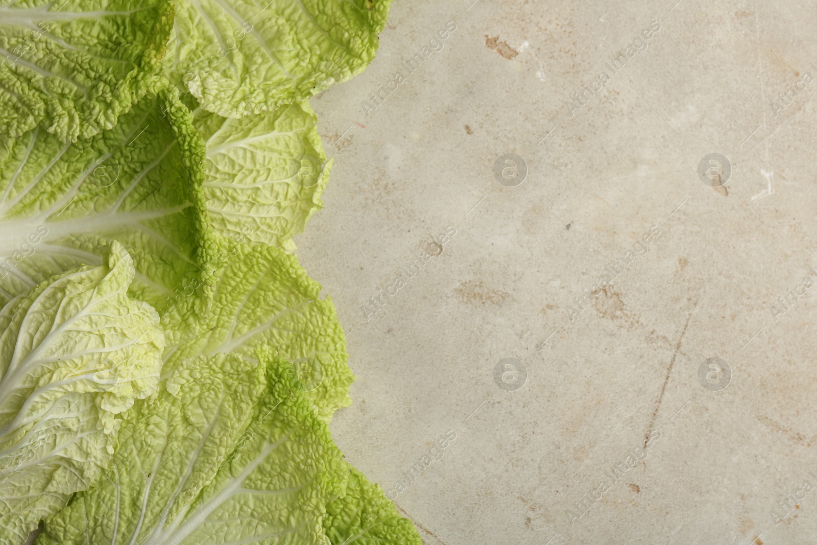 Photo of Fresh Chinese cabbage leaves on gray textured table, top view. Space for text