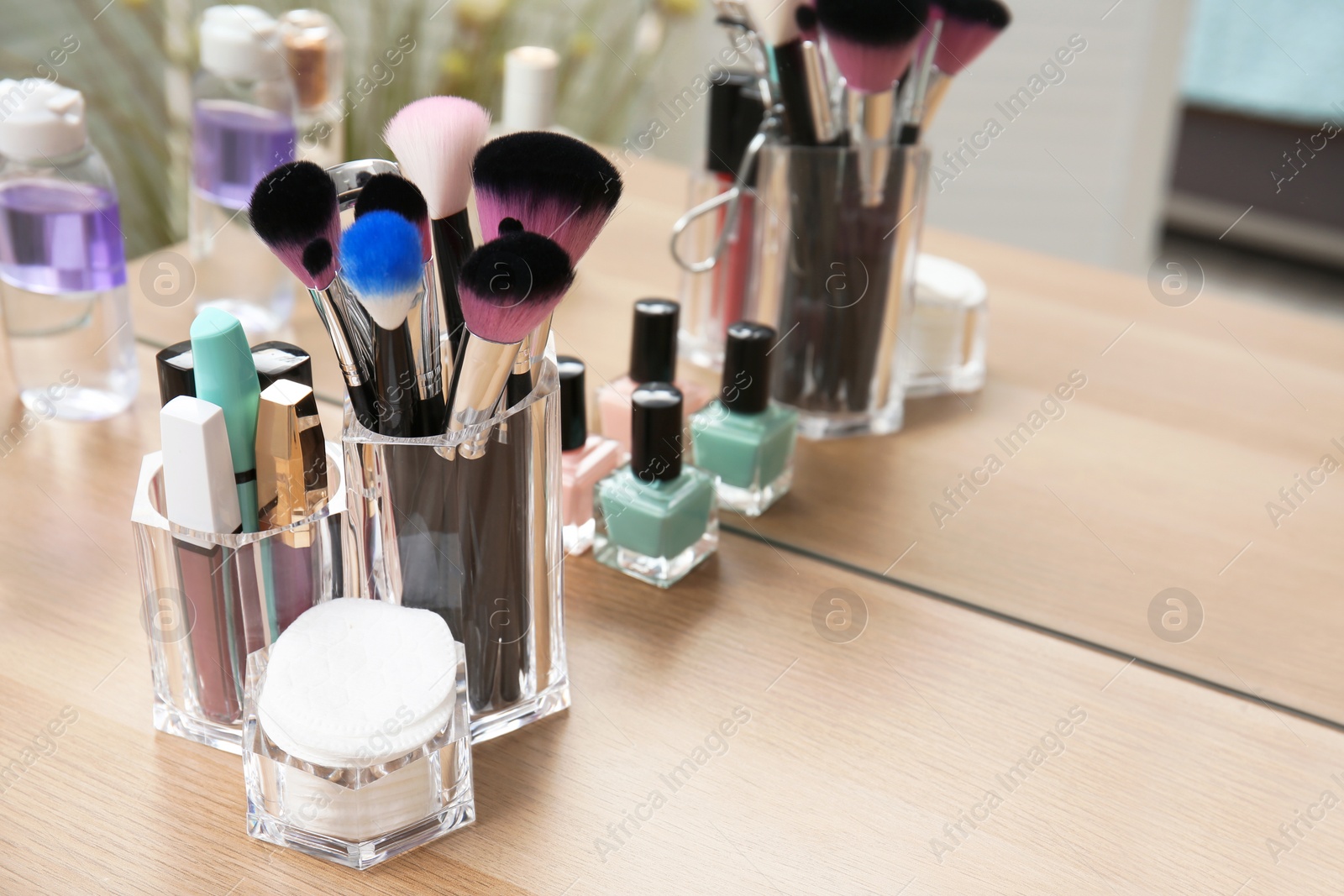 Photo of Organizer with makeup cosmetic products on wooden table near mirror