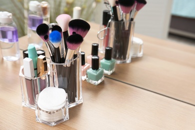 Photo of Organizer with makeup cosmetic products on wooden table near mirror