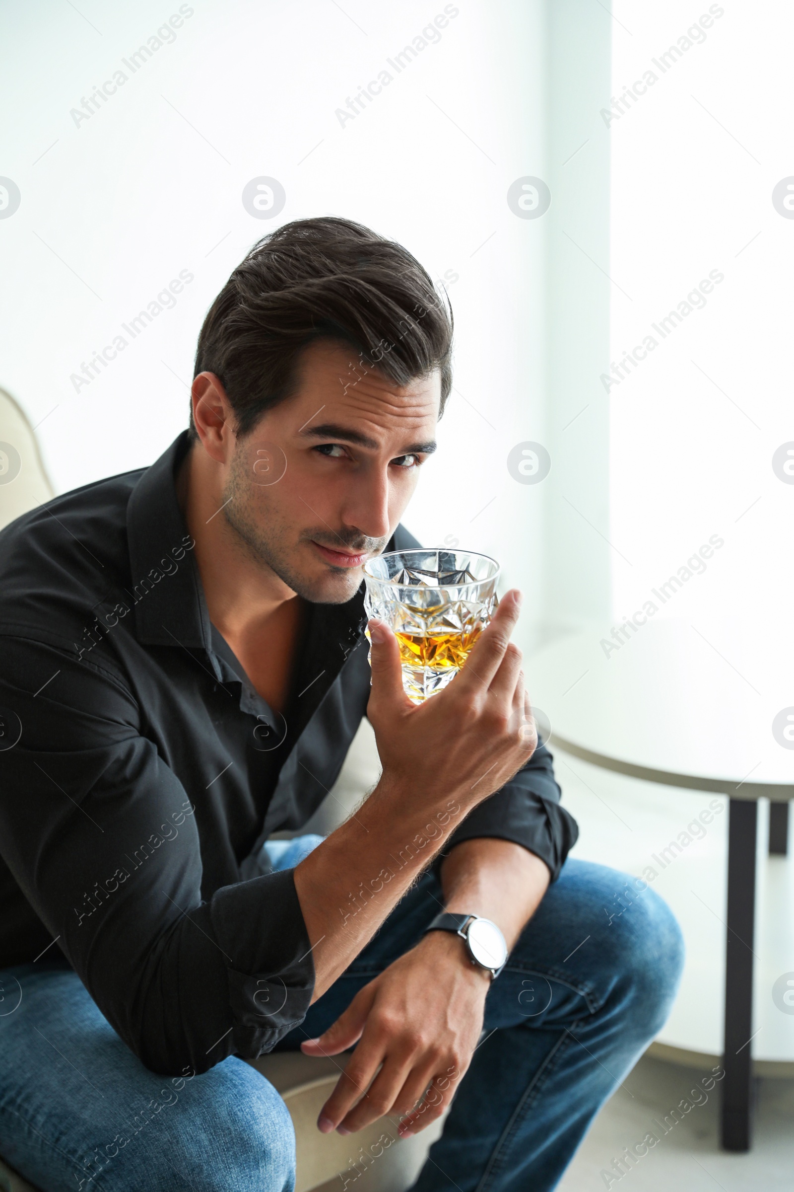 Photo of Young man with glass of whiskey at home