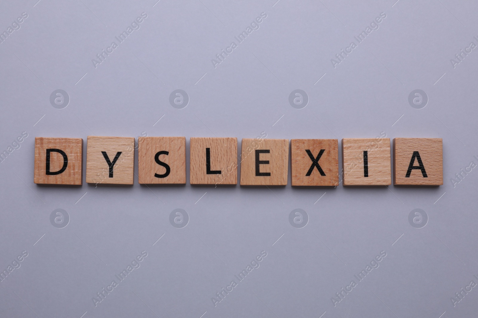 Photo of Wooden tiles with word Dyslexia on light grey background, flat lay