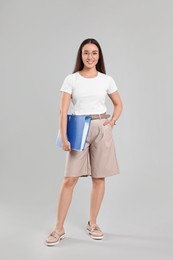 Happy woman with folder on light gray background