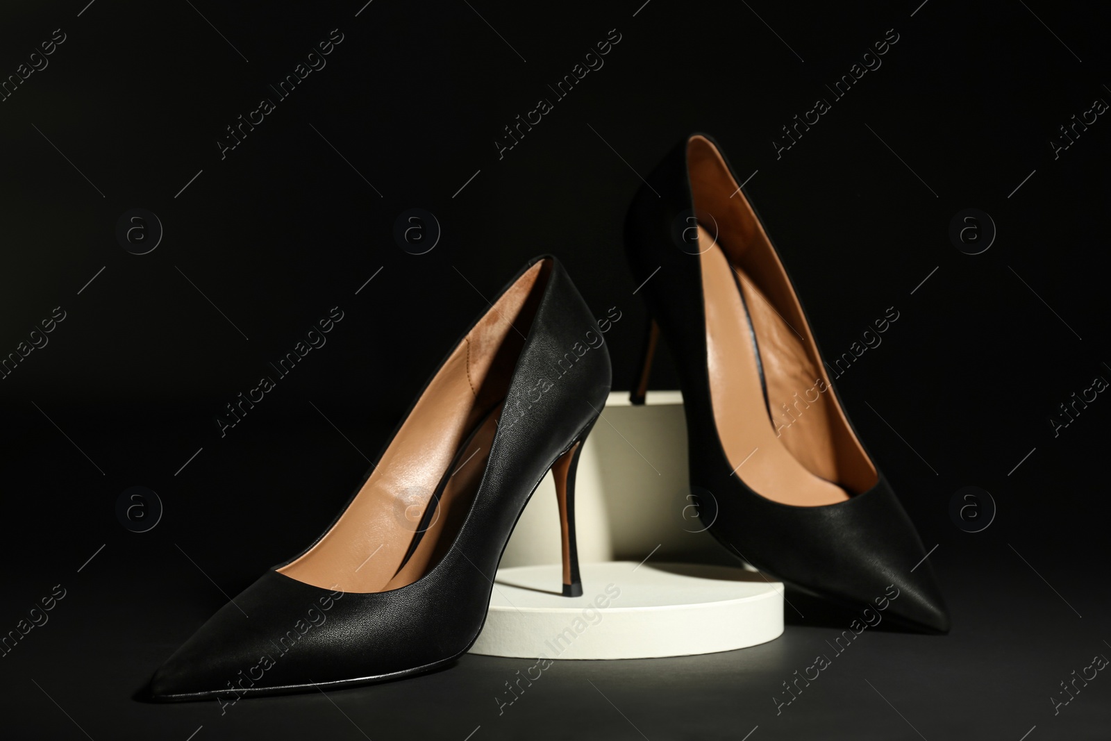 Photo of Pair of elegant high heel shoes on black background