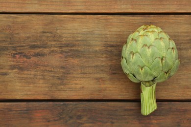 Photo of Fresh raw artichoke on wooden table, top view. Space for text