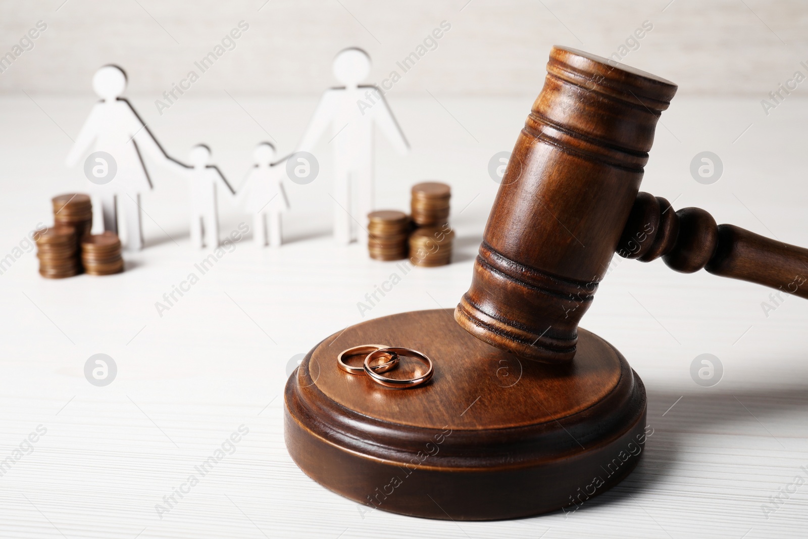 Photo of Divorce concept. Gavel and wedding rings on white wooden table, space for text