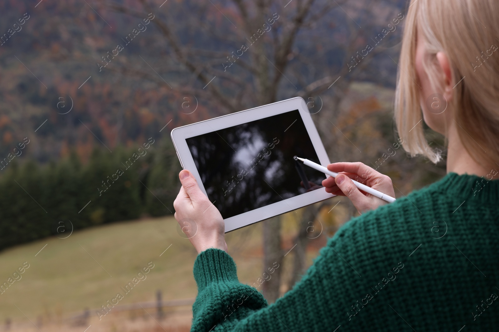 Photo of Young woman drawing on tablet in mountains, closeup