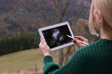 Photo of Young woman drawing on tablet in mountains, closeup