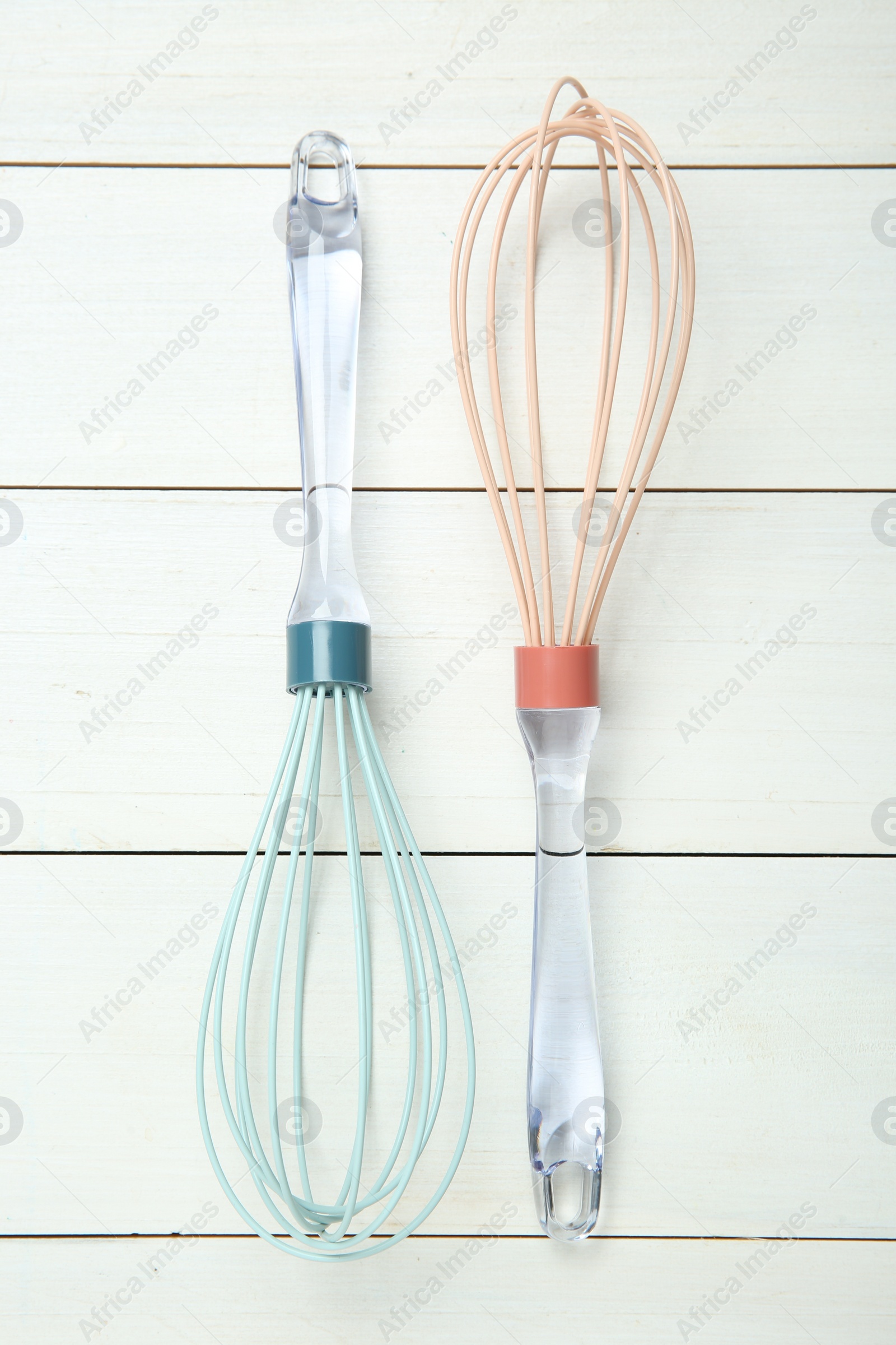 Photo of Two whisks on white wooden table, top view