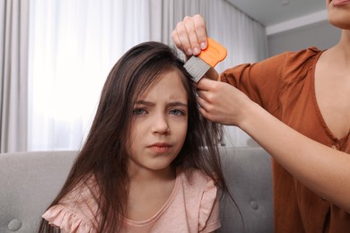 Photo of Mother using nit comb on her daughter's hair indoors. Anti lice treatment