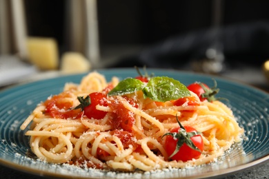 Photo of Tasty pasta with basil, tomatoes and cheese on table, closeup