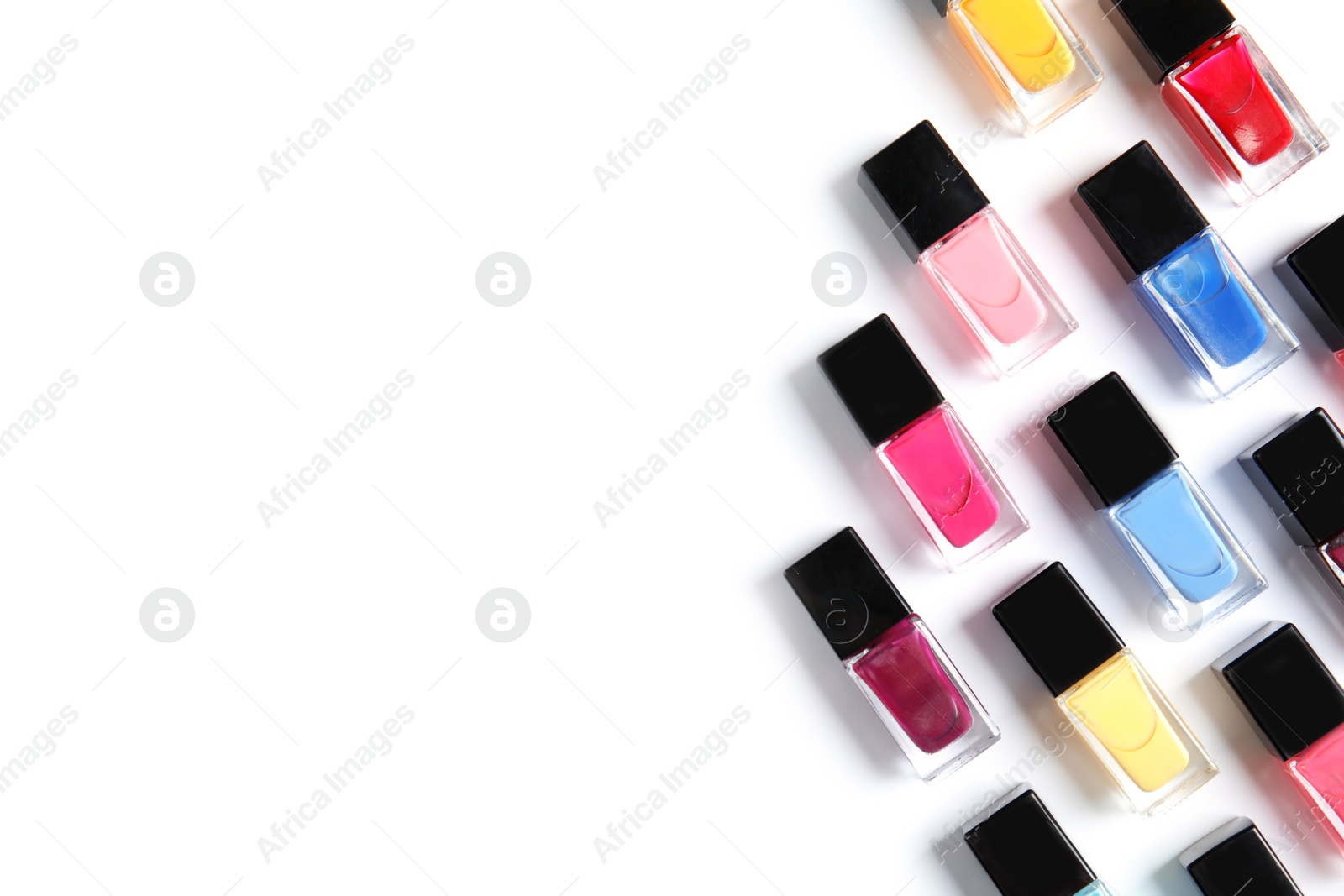 Photo of Bottles of bright nail polish on white background, top view