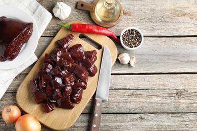 Photo of Cut raw beef liver and products on wooden table, flat lay. Space for text