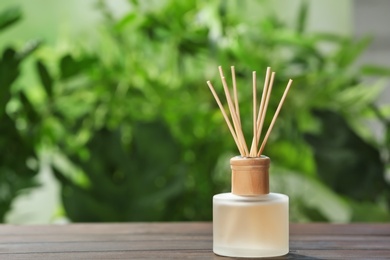 Photo of Aromatic reed freshener on table against blurred background