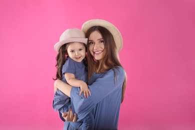 Photo of Young mother and little daughter with hats on pink background