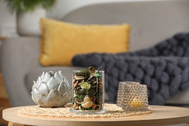 Glass jar with aromatic potpourri of dried flowers and different decor on wooden table indoors