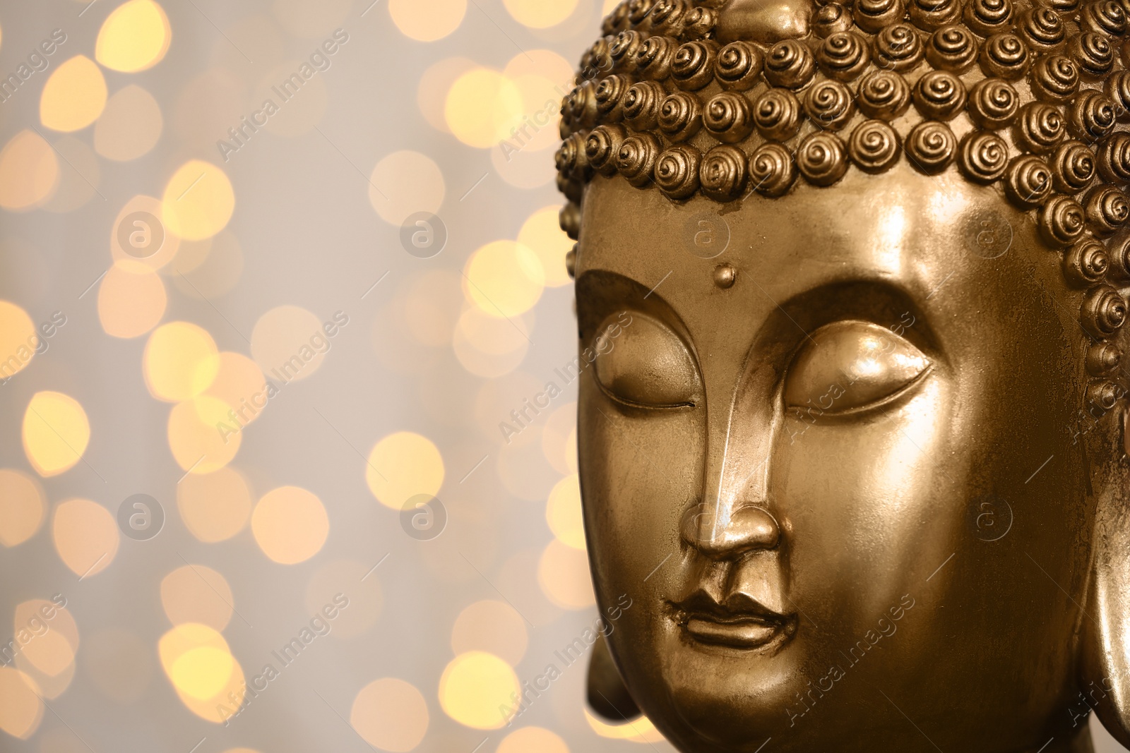 Photo of Buddha statue against blurred lights, closeup. Space for text