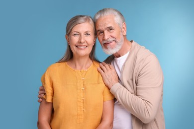 Photo of Portrait of happy affectionate senior couple on light blue background