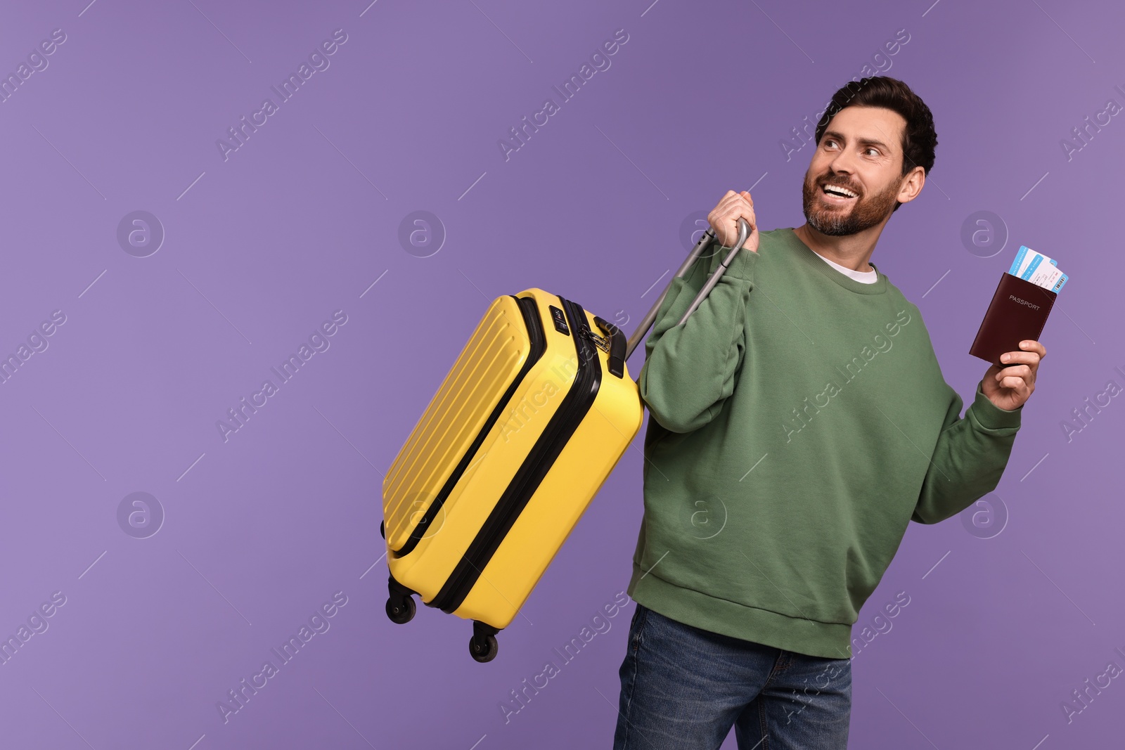 Photo of Smiling man with passport, tickets and suitcase on purple background. Space for text