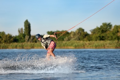 Photo of Teenage boy wakeboarding on river. Extreme water sport