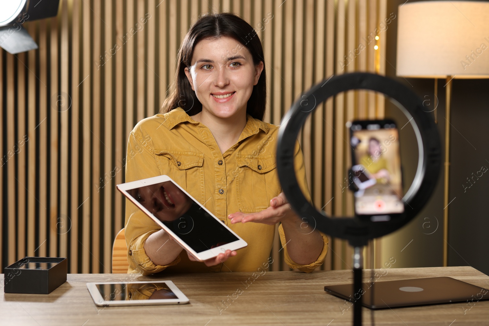 Photo of Smiling technology blogger recording video review about tablets at home