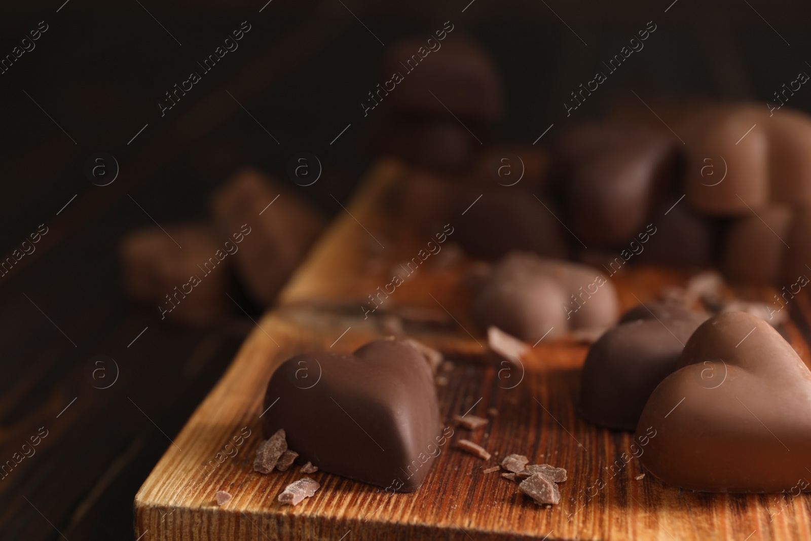 Photo of Beautiful heart shaped chocolate candies on wooden board, closeup with space for text