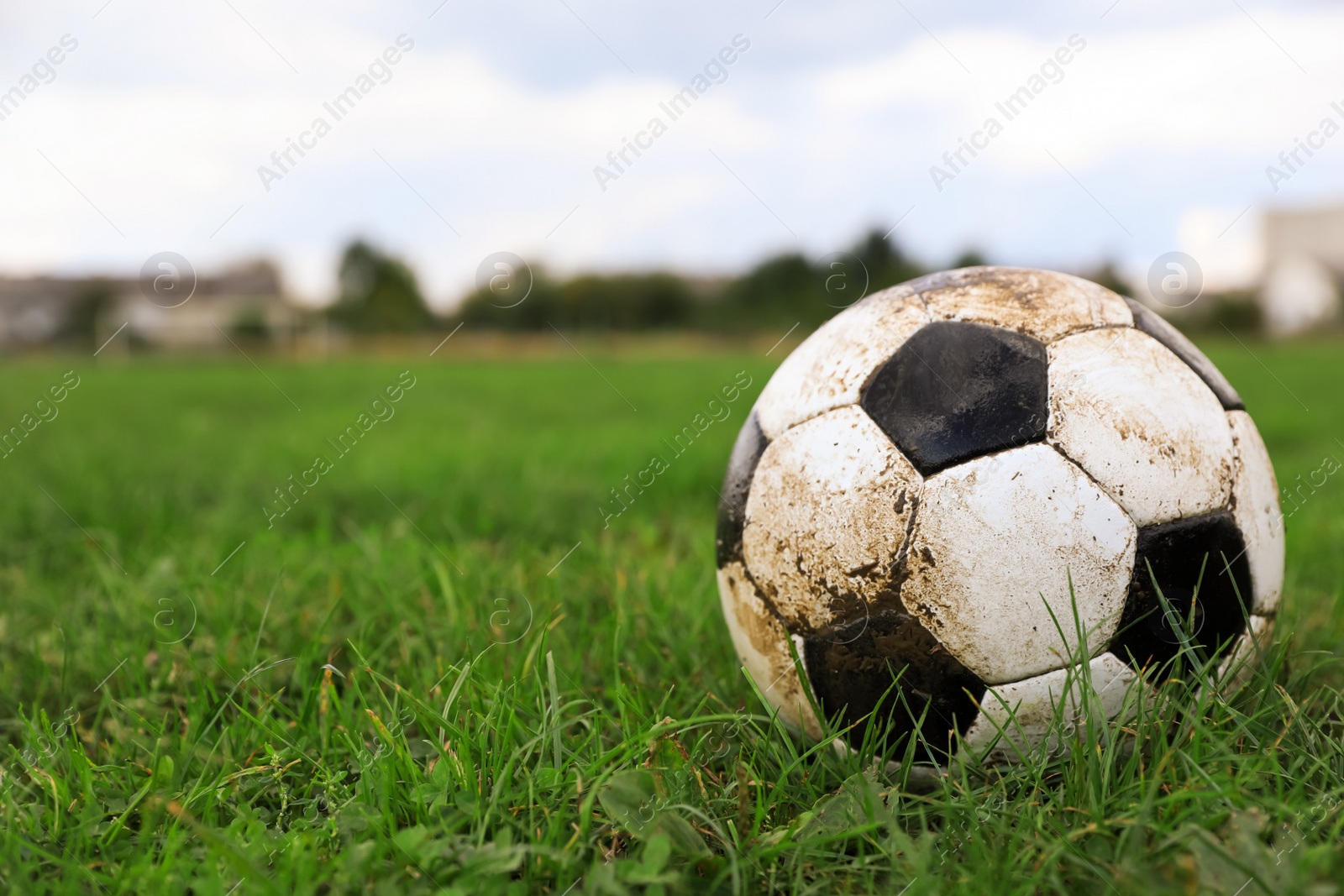 Photo of Dirty soccer ball on green grass outdoors, space for text