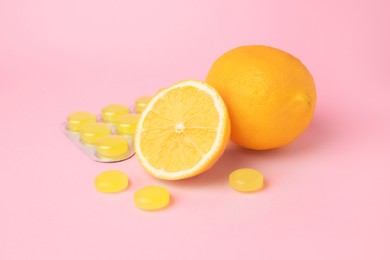 Cough drops and fresh lemons on pink background