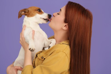 Photo of Woman kissing her cute Jack Russell Terrier dog on violet background
