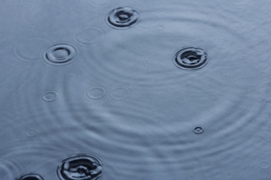 Photo of Rain drops falling down into puddle outdoors