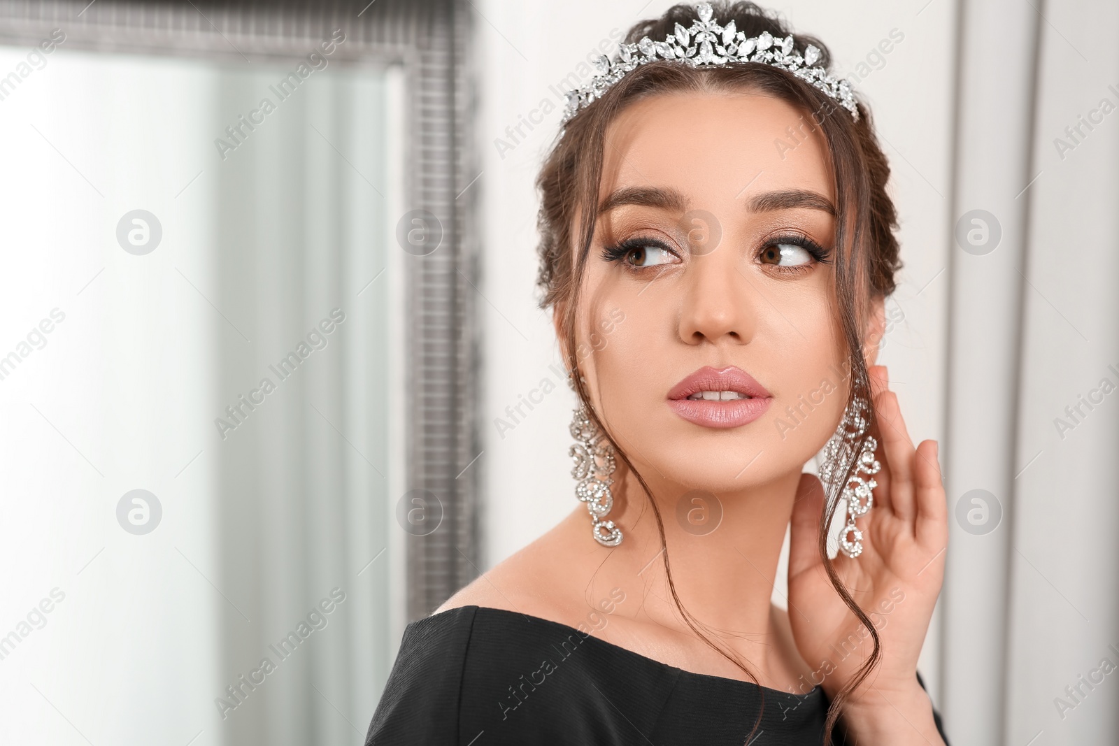 Photo of Beautiful young woman wearing luxurious tiara indoors, space for text