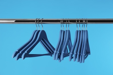 Metal rack with clothes hangers on color background