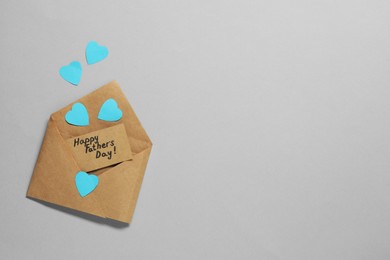 Photo of Card with phrase Happy Father's Day and paper hearts on grey background, top view. Space for text