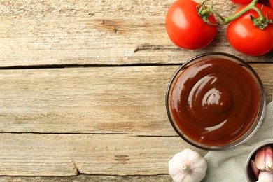 Photo of Flat lay composition with tasty barbeque sauce in bowl on wooden table. Space for text