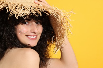 Beautiful happy woman in straw hat with sun protection cream on her face against orange background, space for text