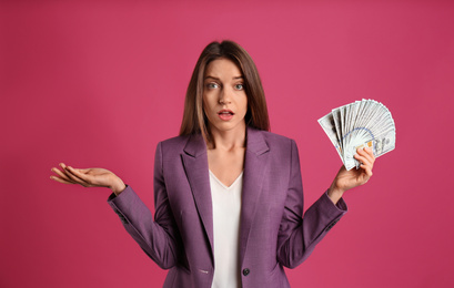 Photo of Emotional young woman with money on pink background