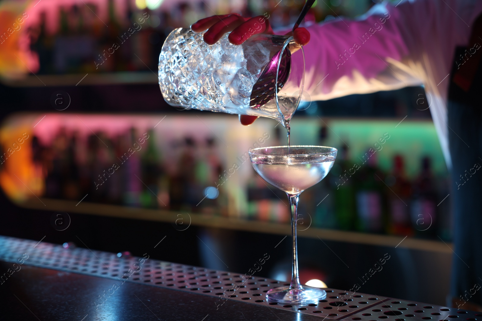 Photo of Bartender making fresh alcoholic cocktail at counter in bar, closeup