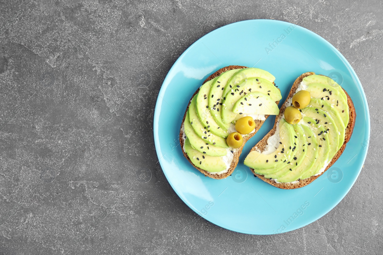 Photo of Crisp rye toasts with avocado, cream cheese and olives on plate, top view