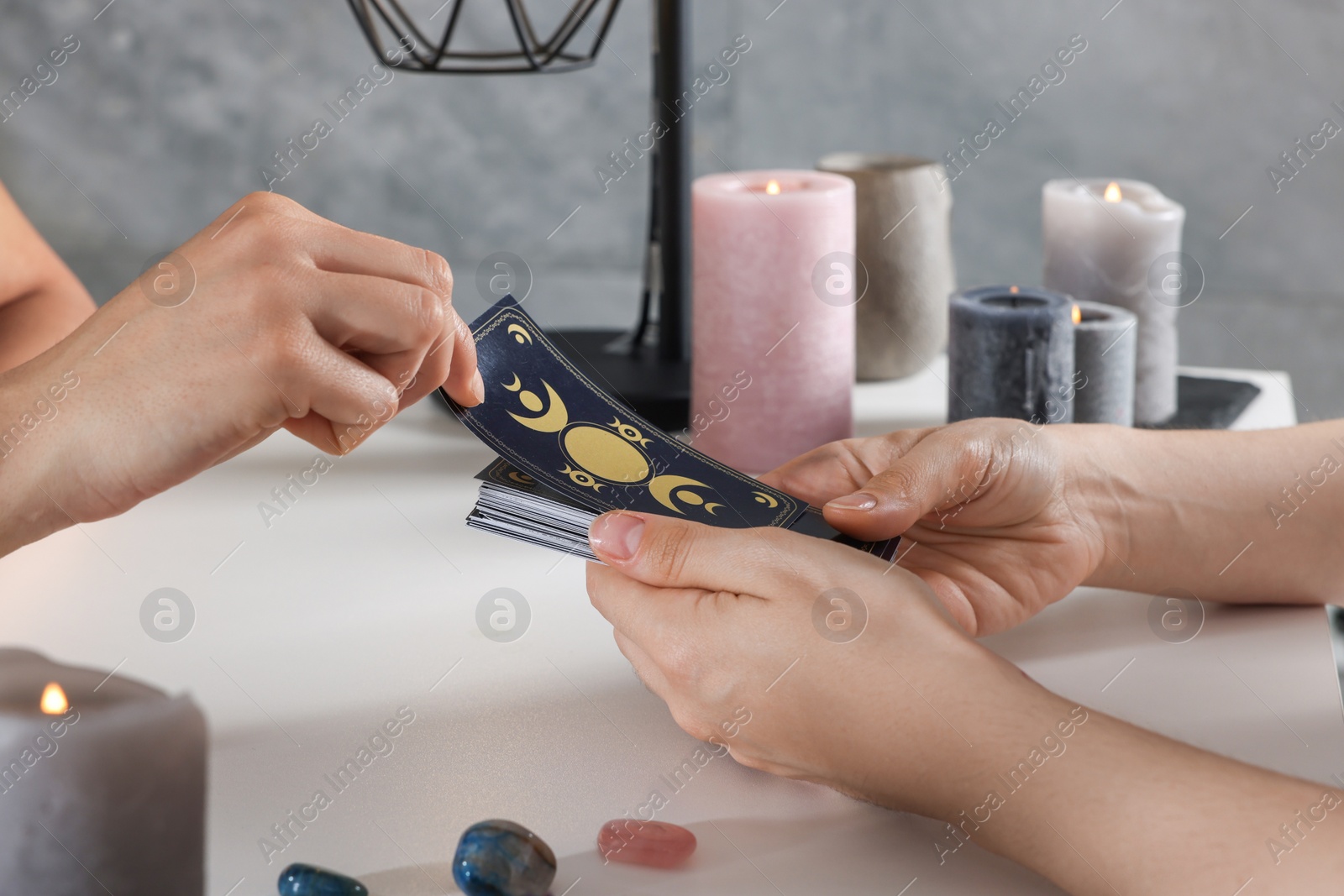 Photo of Astrologer predicting client's future with tarot cards at table indoors, closeup