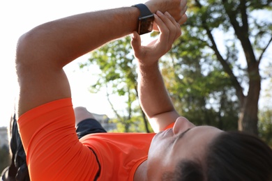 Photo of Man checking fitness tracker during training outdoors, closeup