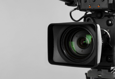 Photo of Modern professional video camera on light background, closeup